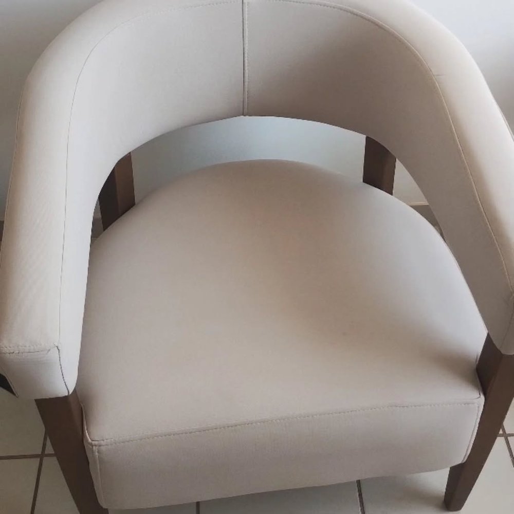 Poltrona estofada em tom claro, com estrutura em madeira